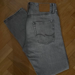 Grå jeans från Jack & Jones - Snygga grå jeans från Jack & Jones i storlek 29/32. Jeansen är i bra skick och har endast lite slitage men är inget som syns vid användning. Modellen heter ”Loose Chris”. Endast 79kr!! 