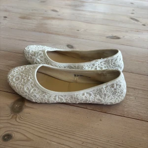 Vita spetsballerinaskor från VOX - Söta vita ballerinaskor från VOX med blommigt spetsmönster. Skorna är använda och på insidan av ena skon har tyget släppt lite men inget som syns vid användning. Annars bra skick! Skriv om ni har någon fråga💕