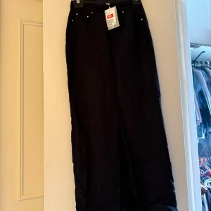 Svarta linnebyxor från H&M, strl 32 - En Snygg svart linnekjol från H&M i storlek 32. Kjolen är rak , hög midja och praktiska fickor både fram och bak. Tillverkad i en skön linneblandning som passar perfekt för varmare dagar.