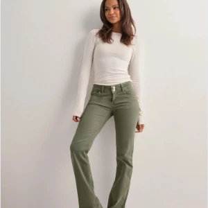 Gröna bootcut jeans Från Nelly  - Snygga lågmidjade gröna jeans med bootcut-snitt och broderade detaljer på bakfickorna. Byxorna har vita sömmar och inte gröna. Fråga gärna efter fler bilder.