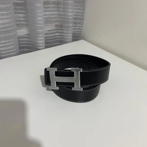 Svart bälte med silver loggan ”H” - Säljer ett svart bälte med silver loggan ”H”!! Dm vid intresse!! Kan gå ner i pris!!