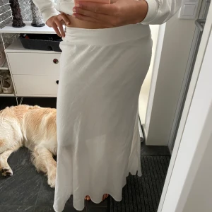 Vit långkjol med mjuk känsla - Säljer en vit långkjol med enkel och clean look. Kjolen har en lätt utsvängd form och bred midjeresår som sitter bekvämt. Perfekt för dig som gillar en stilren och fräsch vibe. Materialet känns mjukt och flowy, vilket gör den superenkel att bära.