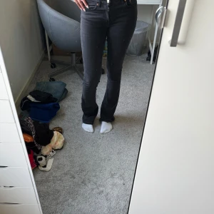 Svarta bootcut jeans med låg midja - Säljer ett par svarta jeans med bootcut-modell och låg midja. Jeansen har klassiska fem fickor, raka ben som blir lite utsvängda nertill och snygga sömmar. Perfekta för dig som gillar en tidlös och clean look. Tall modell