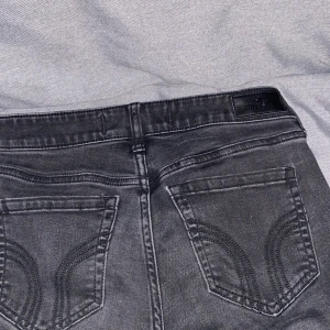 Svarta bootcut jeans från Hollister - Säljer ett par svarta bootcut jeans från Hollister med låg midja. Jeansen har klassiska bakfickor med snygga sömdetaljer och är tillverkade i stretchig bomullsdenim.  Säljer ett par likadana i ljusblå, så det är exakt samma mått❤️passar dig perfekt som är 170 eller lite längre.