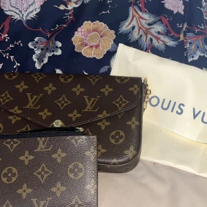  axelväska brun - Säljer en axelväska i brunt monogrammönster med guldiga kedjedetaljer. Ingår plånbok & dustbag.