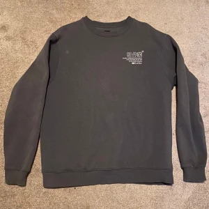 Mörkgrå sweatshirt River Island L - Grå River Island sweatshirt med tryck både fram och bak. Trycket har asiatiska tecken och engelsk text. På ryggen står det bland annat "GLOBAL COMMUNICATIONS PREFIX CIVILIAN MADE UTILITY W/W AFTER HOURS STUDIOS 2020". Använd 6-7 gånger, tvättad efteråt. 