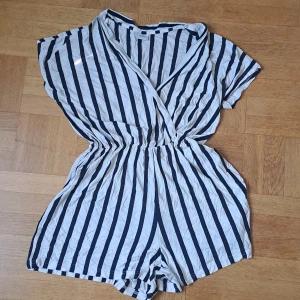 Randig romper  - Snygg vit och marinblå randig romper från Jacqueline de Yong. Modellen har omlott framtill, resår i midjan och korta ärmar. Använd sparsamt 🩷