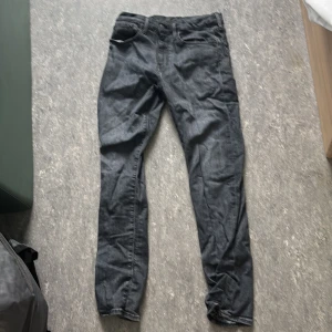 Svarta jeansbyxor i slim fit - Säljer ett par svarta jeansbyxor med klassisk femficksdesign och smal passform. Byxorna har normal midja och raka ben, perfekta till sneakers eller boots. Materialet är jeans och färgen är mörk svart.