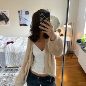 Beige pälströja från Gina Tricot - Supermjuk och fluffig beige pälsjacka från Gina Tricot. Jackan har lång ärm, öppen framtill och en riktigt cozy känsla. Perfekt för dig som vill ha en trendig och mysig look med lite extra edge. Passar till både jeans och klänning.