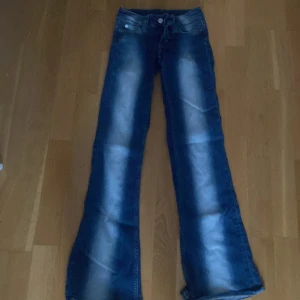 Blå bootcut jeans med slitningar - Snygga blå jeans med bootcut passform och markerade slitningar längs benen. Klassisk femficksmodell med låg midja och dragkedja. Perfekta för dig som gillar retrovibbar och vill ha ett par jeans som sticker ut. Köpta för 399kr! Storlek 23/30 💕