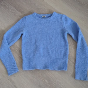 Ljusblå stickad tröja från Pimkie - Superfin ljusblå stickad tröja från Pimkie med rund halsringning och ribbade muddar. Tröjan har en mjuk och fluffig känsla. Långärmad och enkel att matcha med jeans eller kjol.