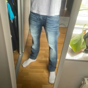 Blå jeans från Jack & Jones 29/30 - Säljer ett par snygga blå jeans från Jack & Jones med slitna detaljer och ljusa tvättade partier. Perfekta för dig som gillar en avslappnad stil.