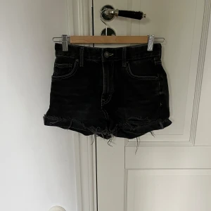 Svarta jeansshorts från Pull&Bear - Svarta jeansshorts från Pull&Bear med råa, fransiga benslut och klassisk femficksdesign. Shortsen har kontrastsömmar och knappgylf. Perfekta för en avslappnad stil under varma dagar. Säljer för att de är för små för mig.