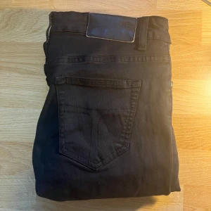 Tiger of sweden jeans - Svarta jeansbyxor från Tiger of sweden. klassisk femficksdesign och smal passform. Byxorna har en enkel stil utan synliga loggor och är perfekta för en stilren look. Passar dig som gillar en modern och enkel stil. Byxorna är i W30/L30. Passformen liknar Dondup George.