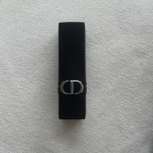 Rouge Dior läppstift 625 Mitzah - Säljer ett Rouge Dior läppstift i nyansen 625 Mitzah. Hylsan är svart med silverdetaljer och CD-logga. Läppstiftet har en klassisk rund form och ger en elegant, bärig färg med satinfinish.Kommer utan förpackning, oanvänd och otestad, om du köper fler av dessa läppstift kan jag tänka mig bättre pris. Rensning inför flytt. Vissa märken på själva skalet på läppstiftet då jag förvarat alla i samma låda 