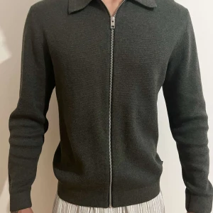 Mörkgrå stickad cardigan jacka med dragkedja - Snygg mörkgrå stickad cardigan jacka med dragkedja framtill och klassisk krage. Ny pris 899kr ( Använd cirka 5-6 gånger ) 