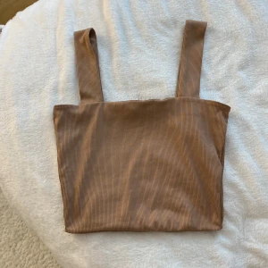 Beige ribbad linnetopp från Amisu - Säljer en beige ribbad linnetopp från Amisu med breda axelband. Toppen har en enkel och stilren design, perfekt att matcha med jeans eller kjol. Superskön och trendig modell!