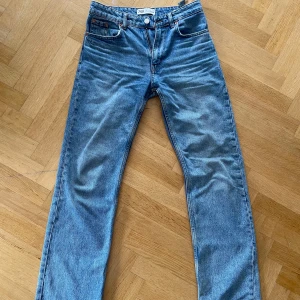  Straight jeans ZARA - Klassiska blå jeans från ZARA med raka ben och normal passform. Jeansen har fem fickor, knapp- och dragkedjegylf samt läderpatch med 'Signature Denim' bak. Perfekta till vardags och lätta att matcha med olika stilar.