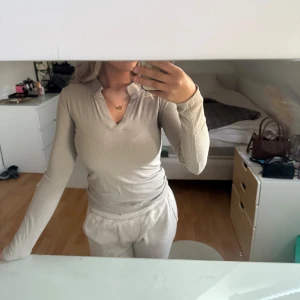 Beige ribbad långärmad tröja med v-ringning - Säljer en beige ribbad långärmad tröja med v-ringning. Tröjan är figurnära och stretchig så även om den är XS så passar den S och säkert M 
