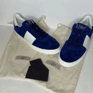 Blå och vita sneakers från Valentino - Säljer ett par blå och vita Valentino sneakers med mockadetaljer och vit sula. Skorna har snörning och en unik sula med camouflage-mönster. Perfekta för dig som vill sticka ut med stilrena och exklusiva sneakers.Snygga Valentino sneakers i blå mocka med vita detaljer. De är i mycket bra skick och redo att användas direkt! Skick:8/10 Allt OG tillkommer förutom kvitto! Hör av er vid intresse, funderingar eller fler bilder