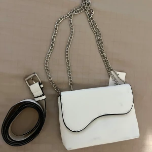 Vit axelväska med silverkedja - Säljer en stilren vit axelväska från Mango med silverfärgad kedjerem. Funkar både som magväska och axelväska