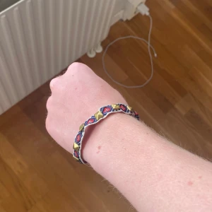 Unikt armband - Snyggt armband med broderat mönster i rött, blått och vitt. Armbandet har guldiga fyrkantiga nitar och justerbart svart knytband. Perfekt accessoar för att ge din stil en färgklick. Skriv vid frågor 😊