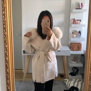 Vit pälsjacka med bälte - Säljer en fluffig vit pälskappa med bred krage och bälte i midjan. Jackan har långa ärmar. Den är i storlek xs. Den är gjord av äkta päls. Har använts 3 gånger men har inga hål eller fläckar. Den är som helt ny. Original priset för den är 3400kr så säljer den för 2800kr. Frakt ingår. Pris kan sänkas via dm.