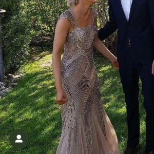 Balklänning  - Glittrig långklänning i champagne med detaljerade paljetter. Klänningen har en ärmlös design och en vacker passform som framhäver figuren. Använd 1 gång, Nypris 3500kr. (Köpt i USA)