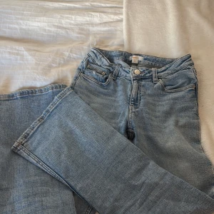 Blå jeans från Gina Tricot - Snygga blå jeans från Gina Tricot med klassisk femficksdesign och knappgylf. Perfekta för en avslappnad stil. De har en rak passform och är tillverkade i ett bekvämt denimtyg.