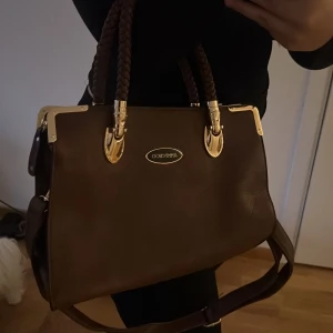 Brun handväska  - Säljer en elegant brun handväska, passar som vardagsväska samt till skolan. Fått väskan som gåva. Snabb affär kan pris diskuteras