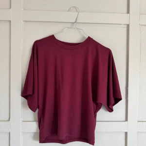 Vinröd t-shirt från 157 - Säljer en stilren vinröd t-shirt från 157. Den har en klassisk rund hals och korta ärmar, perfekt för en avslappnad look. Passar bra till både jeans och shorts. Perfekt för vardagsbruk!