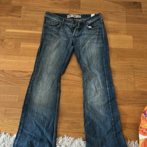Blå jeansbyxor low Waist bootcut  - Säljer ett par klassiska blå jeansbyxor från Levis. De har en straight passform och är tillverkade i slitstarkt denim. Perfekta för en avslappnad stil. Byxorna har fem fickor och en knappgylf.