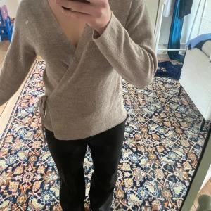Beige omlottopp - Säljer en stilren beige omlottopp med lång ärm och knytning i sidan. 