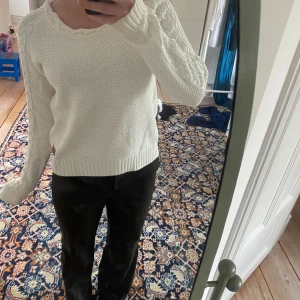 Vit stickad tröja - Säljer en mysig vit stickad tröja med kabelstickat mönster på ärmarna. Tröjan har en rund halsringning och ribbstickade muddar vid ärmslut och nederkant. 