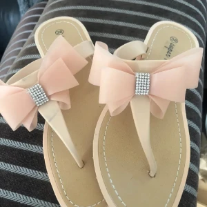 Beige sandaler med rosett 38  - Snygga beige sandaler från Super Mode med en stor rosett och glittrande detaljer på ovansidan. Perfekta för varma sommardagar.