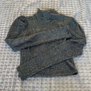 Grå glittrig polotröja - Snygg grå glittrig polotröja med långa ärmar. Perfekt för att lysa upp din garderob med lite glitter. Tröjan har en klassisk polokrage och är både stilren och trendig.