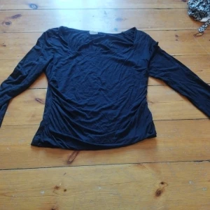 Svart långärmad topp från Stories - Säljer en stilren svart långärmad topp från Stories. Perfekt för en enkel och elegant look. Toppen har en kantig halsringning och är tillverkad i ett mjukt material.