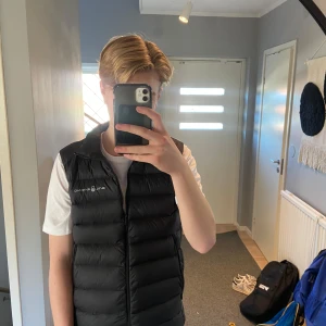 Svart sailracing väst - Snygg svart dunväst från Sail Racing med dragkedja framtill. Perfekt för kyligare dagar och har en stilren design med logotyp på bröstet. Västen är quiltad och ger en sportig look. Perfekt nu inför våren!☀️ Sällan använd och därmed ett toppen skick, det står storlek 170 men passar mig som är 183 alldeles utmärkt så mer stl S/M💫 Vid frågor är det bara att höra av sig! Priset ej hugget i sten men tar inte emot skambud🤝