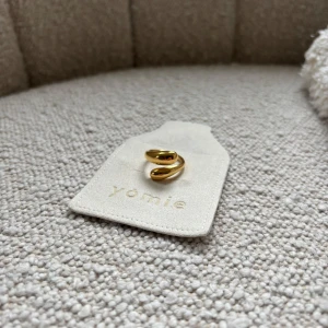 Guldfärgad ring från Yomie - Elegant guldfärgad ring från Yomie med en modern och stilren design. Perfekt för att ge en touch av lyx till din outfit.