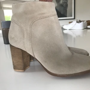 Beige ankelboots mocka Stl 39 - Beige ankelboots med klack. Äkta nubuck/läder. H&M Premium. Klackhöjd mitt bak 8 cm. Bekväma med mjuk innersula. Stl 39, normal storlek. Stängs med dragkedja på sidan. Inga defekter, använd ett fåtal gånger, är i bra begagnat skick. Säljer då de är för stora för mig.  Nypris 800kr