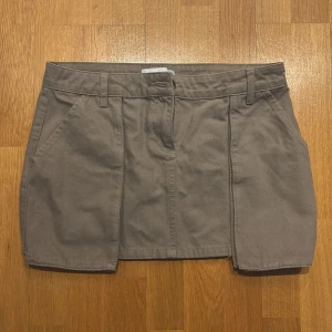 Beige jeanskjol från Josefine HJ x NA-KD - Snygg beige jeanskjol från Josefine HJ x NA-KD med en klassisk design. Kjolen har hällor för bälte och stängs med en knapp framtill. Perfekt för en stilren look. Aldrig använda 