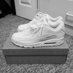 Vita Nike Air Max 90 - Säljer ett par klassiska vita Nike Air Max sneakers. De har en ikonisk design med synlig luftdämpning i sulan och snörning framtill. Perfekta för en stilren look. 10/10 skick box följer med 
