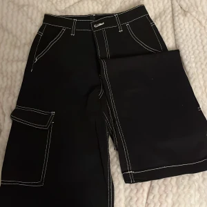 Svarta cargopants från Divided H&M🖤 - Snygga svarta cargopants från Divided med vita kontrastsömmar. Med fickor på sidorna. 🦓🐝