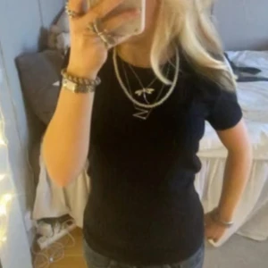 Svart ribbad t-shirt - Säljer en stilren svart ribbad t-shirt med korta ärmar. Perfekt för en enkel och snygg look. Passar bra till jeans eller kjol.