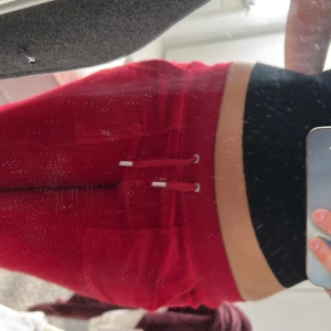 Röda mjukisbyxor från Juicy Couture - Snygga röda mjukisbyxor från Juicy Couture med snörning i midjan och broderad logga på fickan. Perfekta för en avslappnad stil. Tillverkade i mjukt material för extra komfort.