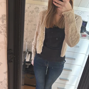 Beige stickad kofta - Säljer en mysig beige stickad kofta med ett vackert mönster. Koftan har långa ärmar och knappar framtill. Perfekt för kyliga dagar och ger en stilren look. Passar bra till jeans eller klänning. Koftan är i xs men skulle säga att den passar som s också.