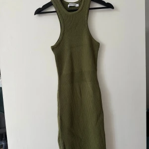 Olivgrön ribbad klänning från Adoore - Snygg olivgrön ribbad klänning från Adoore i storlek 38. Klänningen är ärmlös och har en tight passform som framhäver figuren. Perfekt för en stilren look. 🌿
