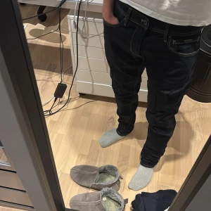 Pepe Jeans mörkblå tapered jeans 32/32 - Säljer ett par mörkblå jeans från Pepe Jeans i modellen Tapered. Jeansen har snygga kontrastsömmar, klassisk femficksdesign och skinnpatch bak i midjan. Tillverkade i bomull med lite elastan för extra komfort. Perfekta om du gillar en modern, avsmalnande passform.