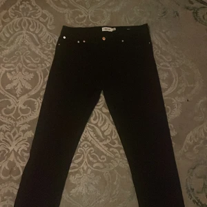 Svarta jeansbyxor från !Solid - Snygga fräscha svarta jeansbyxor från !Solid, modell SDRYDER. Klassisk femficksdesign med silverfärgade nitar och knappdetalj. Byxorna har en rak passform och är tillverkade i ett mjukt bomullsmaterial med stretch för extra komfort. Byxorna är elastiska och kommer i bekväm material. Dem är inte skinny jeans utan dem är regular och mjuka som låter benen röra sig fritt och andas. Byxorna har bara används 3 gånger.