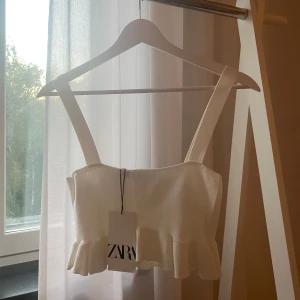 Vitt Linne från Zara Storlek S - Superfint vitt croppat linne från Zara med breda axelband och volangkant nedtill. Oanvänt med alla lappar kvar 🤍